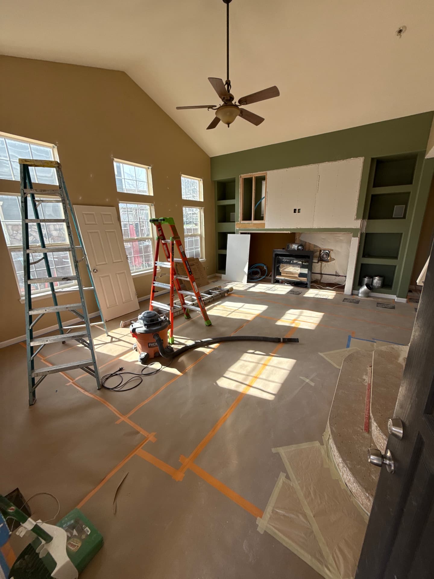 Living room under construction with ladders and unfinished fireplace wall