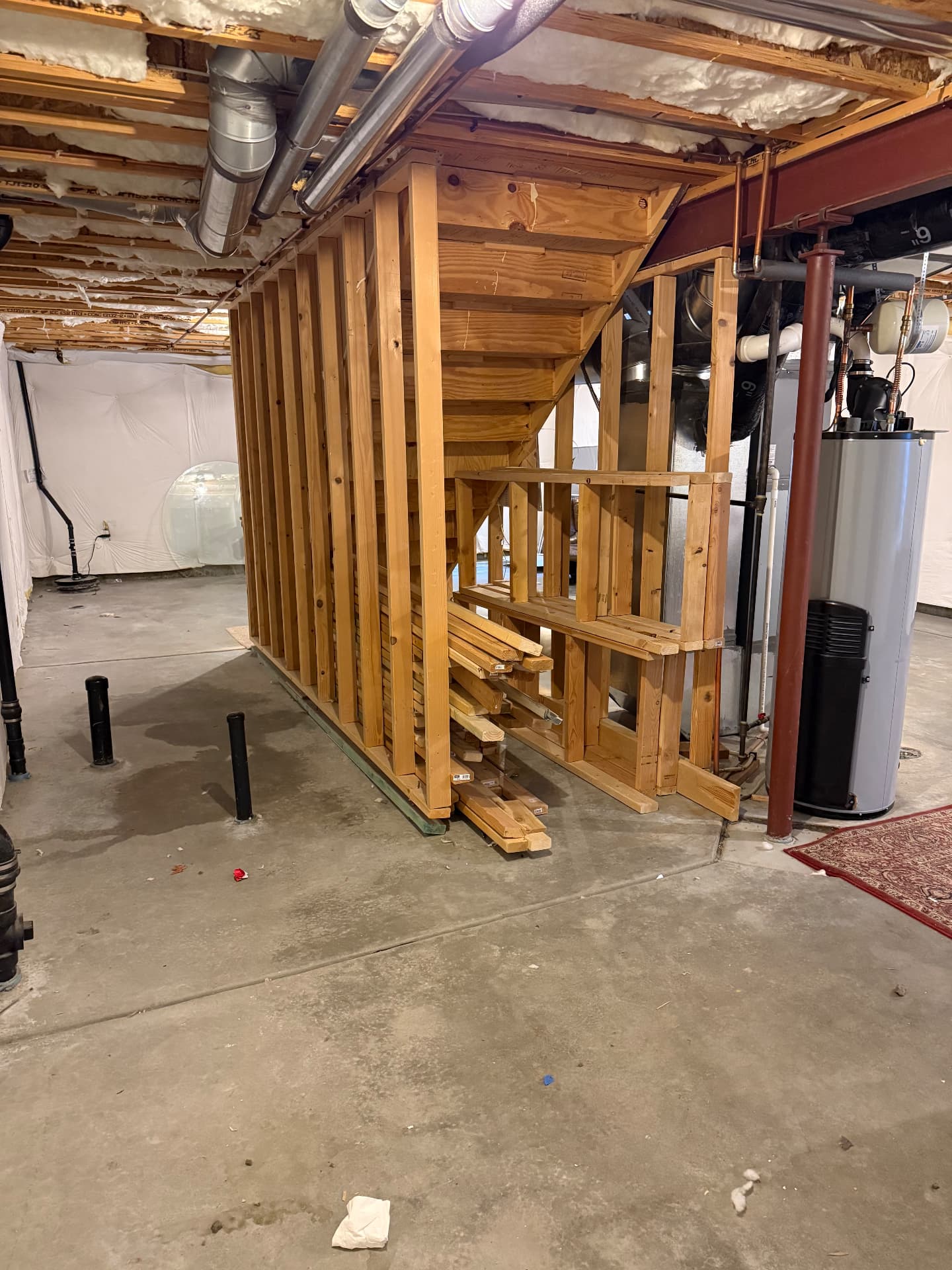 Unfinished basement with exposed framing under the stairs