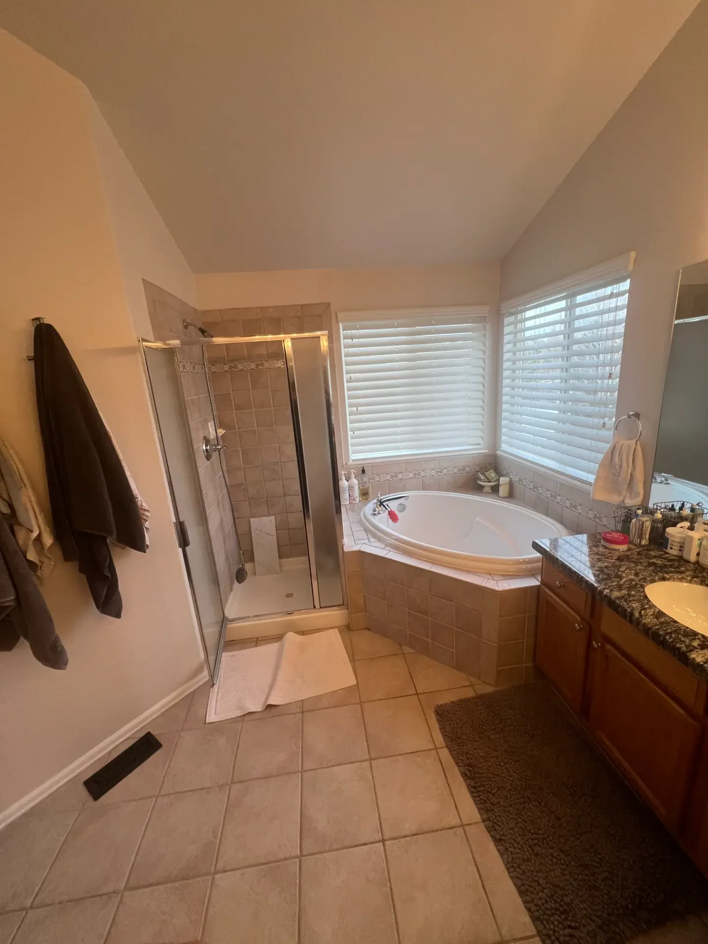 Dated bathroom with corner tub and tiled shower before JR Burcham remodel