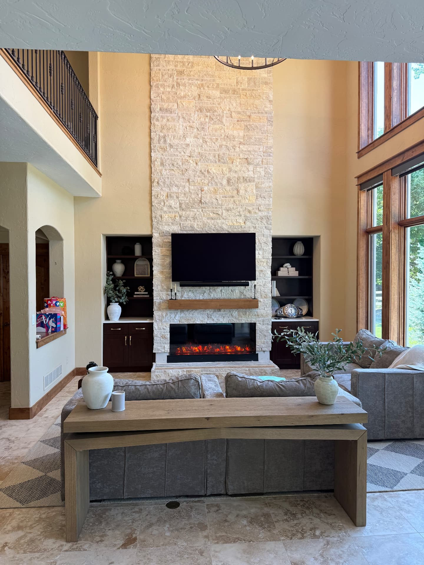 Finished two-story limestone fireplace wall with linear fireplace and built-in shelving