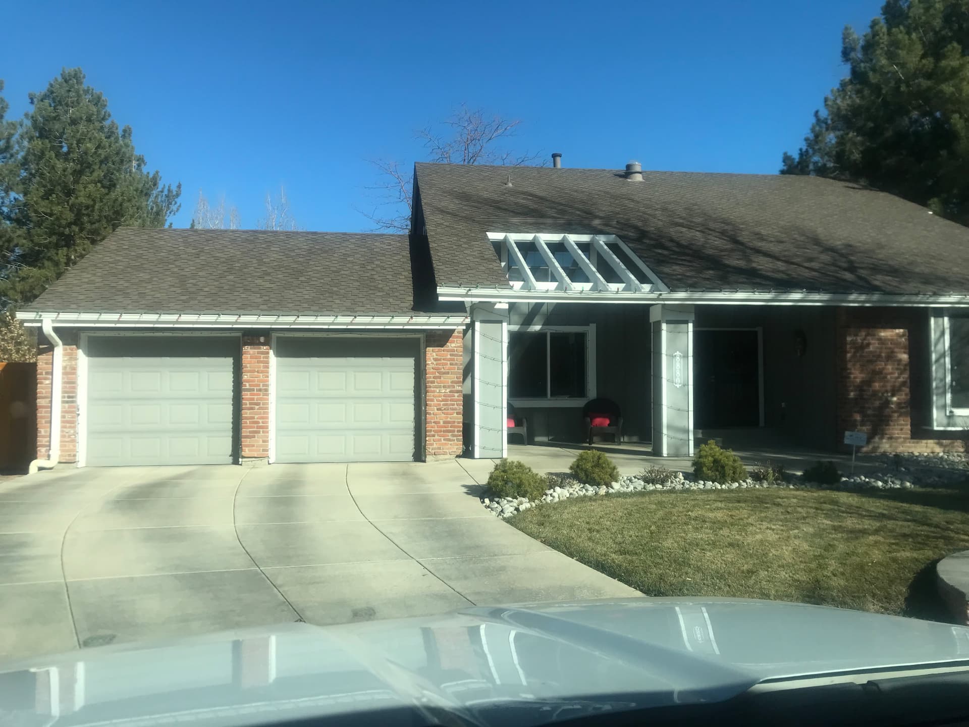 Home exterior with faded gray paint and white garage doors before update