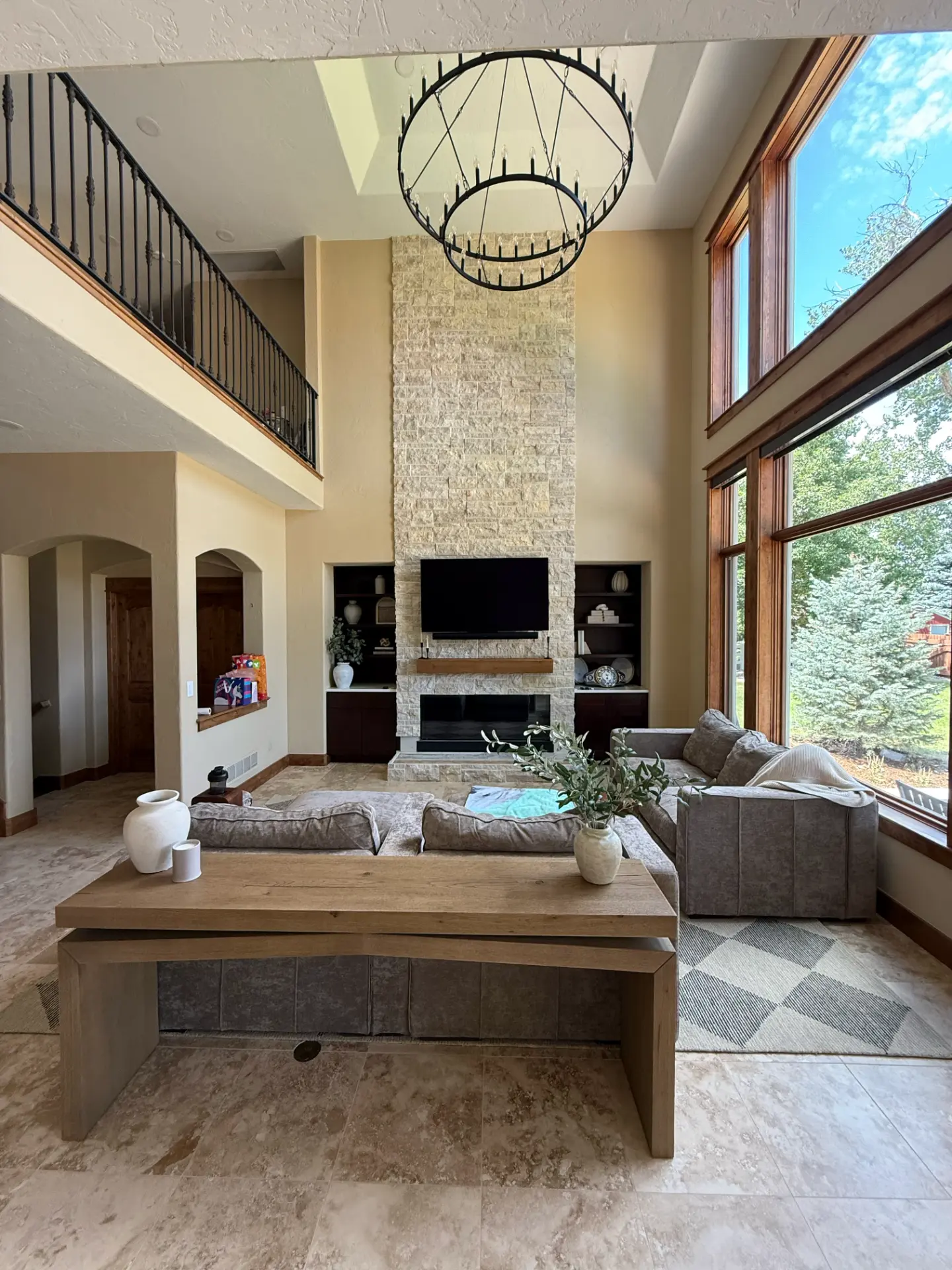 Completed two-story fireplace wall with stacked stone, built-ins, and chandelier by JR Burcham