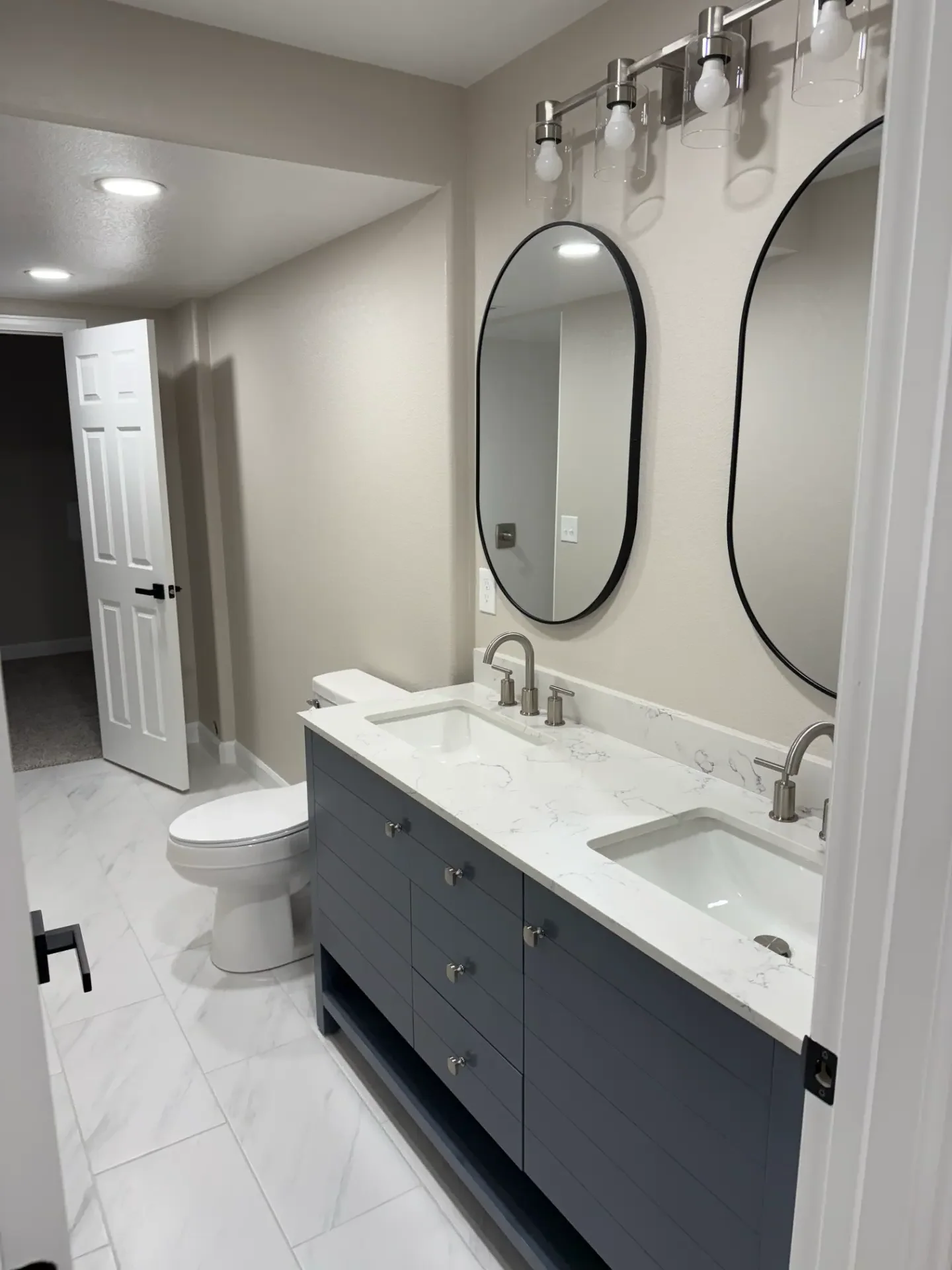 Finished basement bathroom with double vanity and oval mirrors by JR Burcham