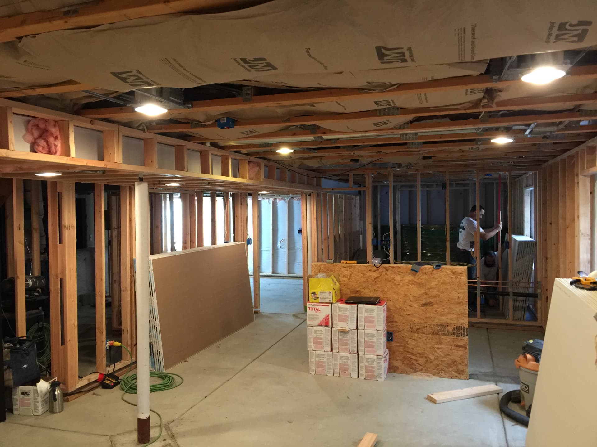 Unfinished basement with open framing and concrete floor before finish