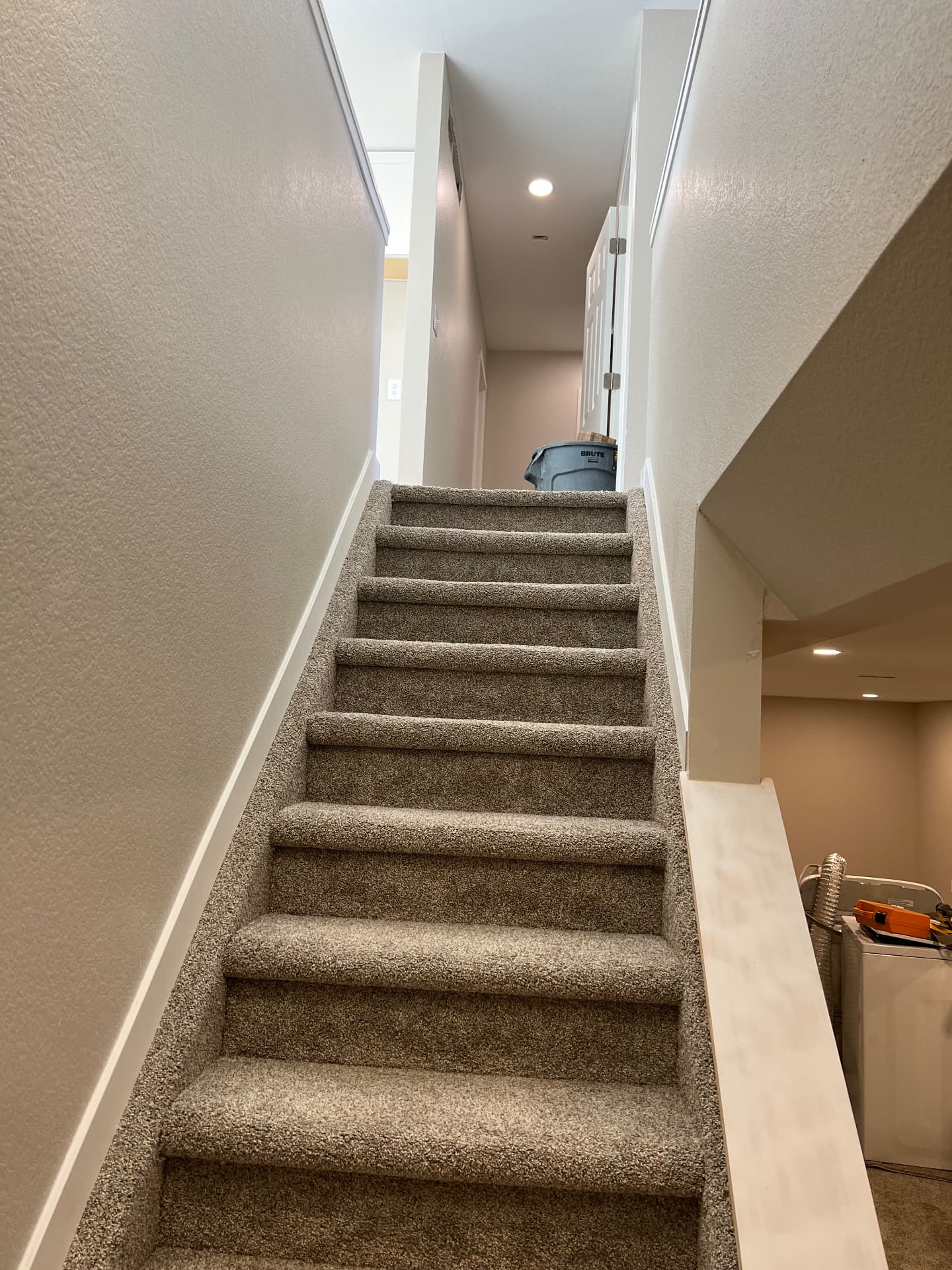 Rebuilt staircase with drywall half walls, white trim, and new carpet