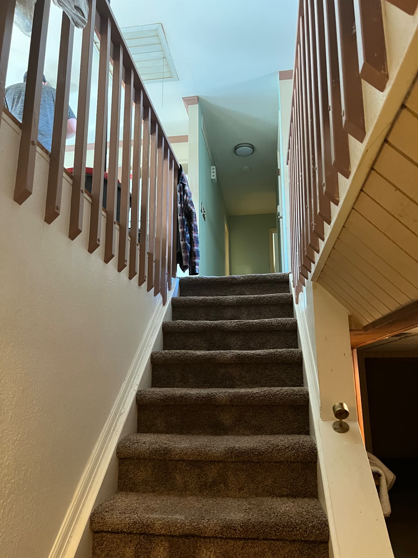 Old staircase with brown wood spindles and worn carpet before remodel
