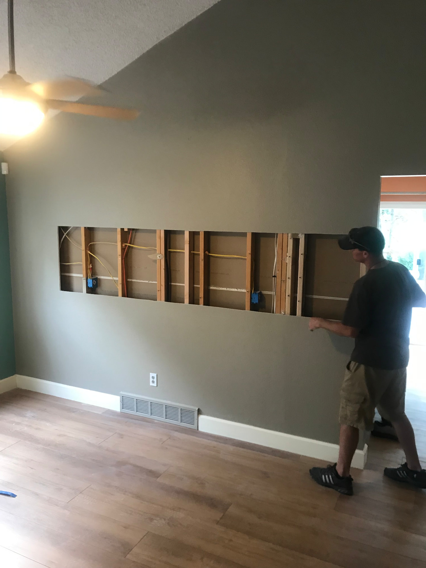 Wall being opened between living room and kitchen with exposed framing