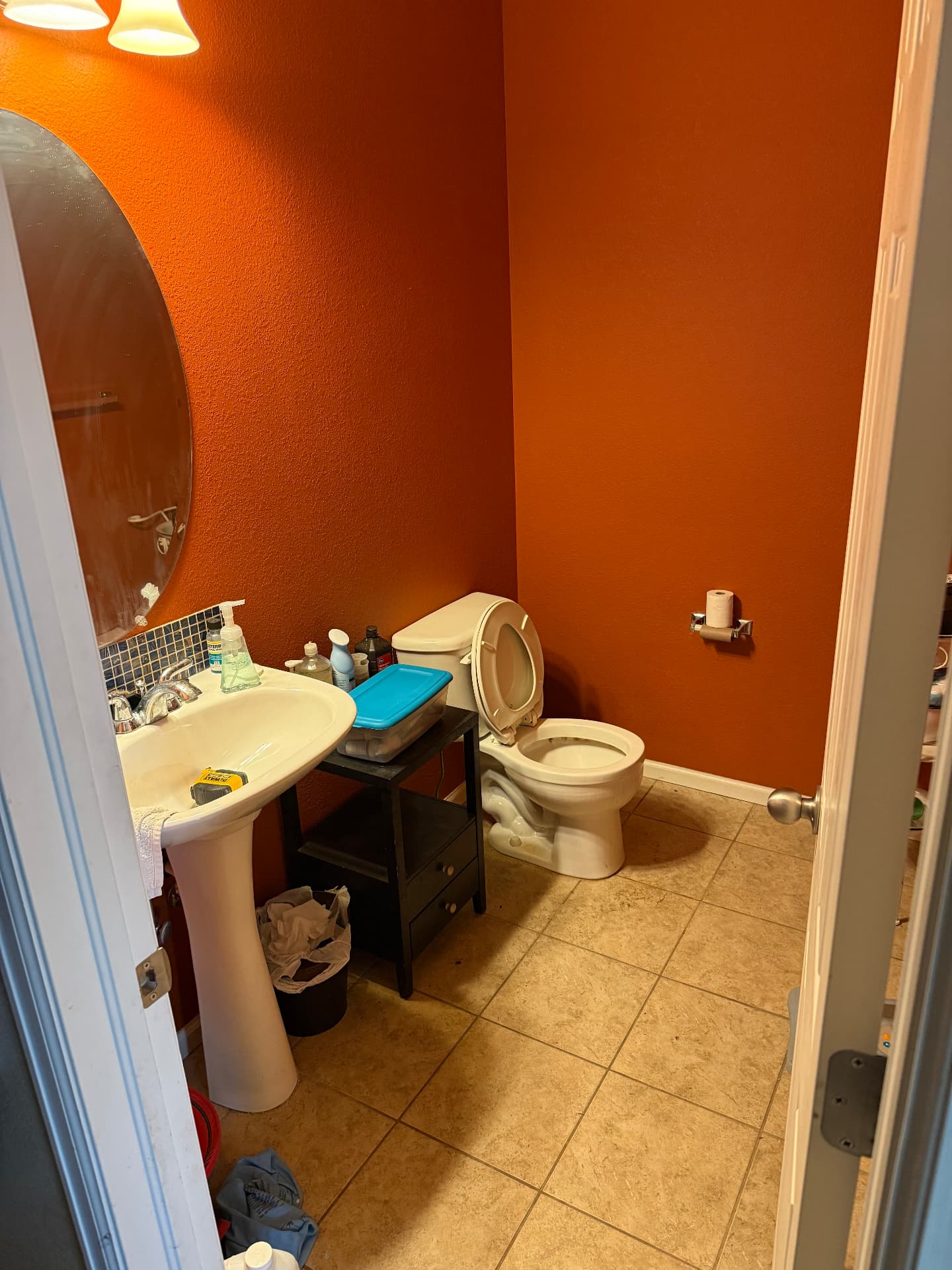 Small powder room with orange walls and pedestal sink before remodel