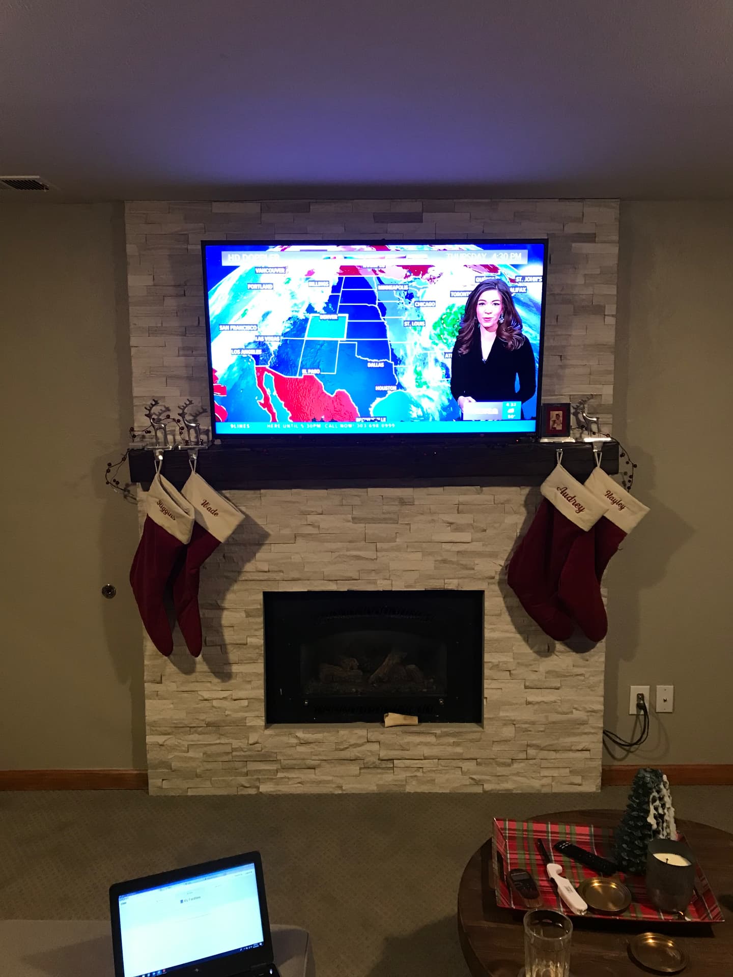 Modern white stacked stone fireplace with dark floating mantel and TV