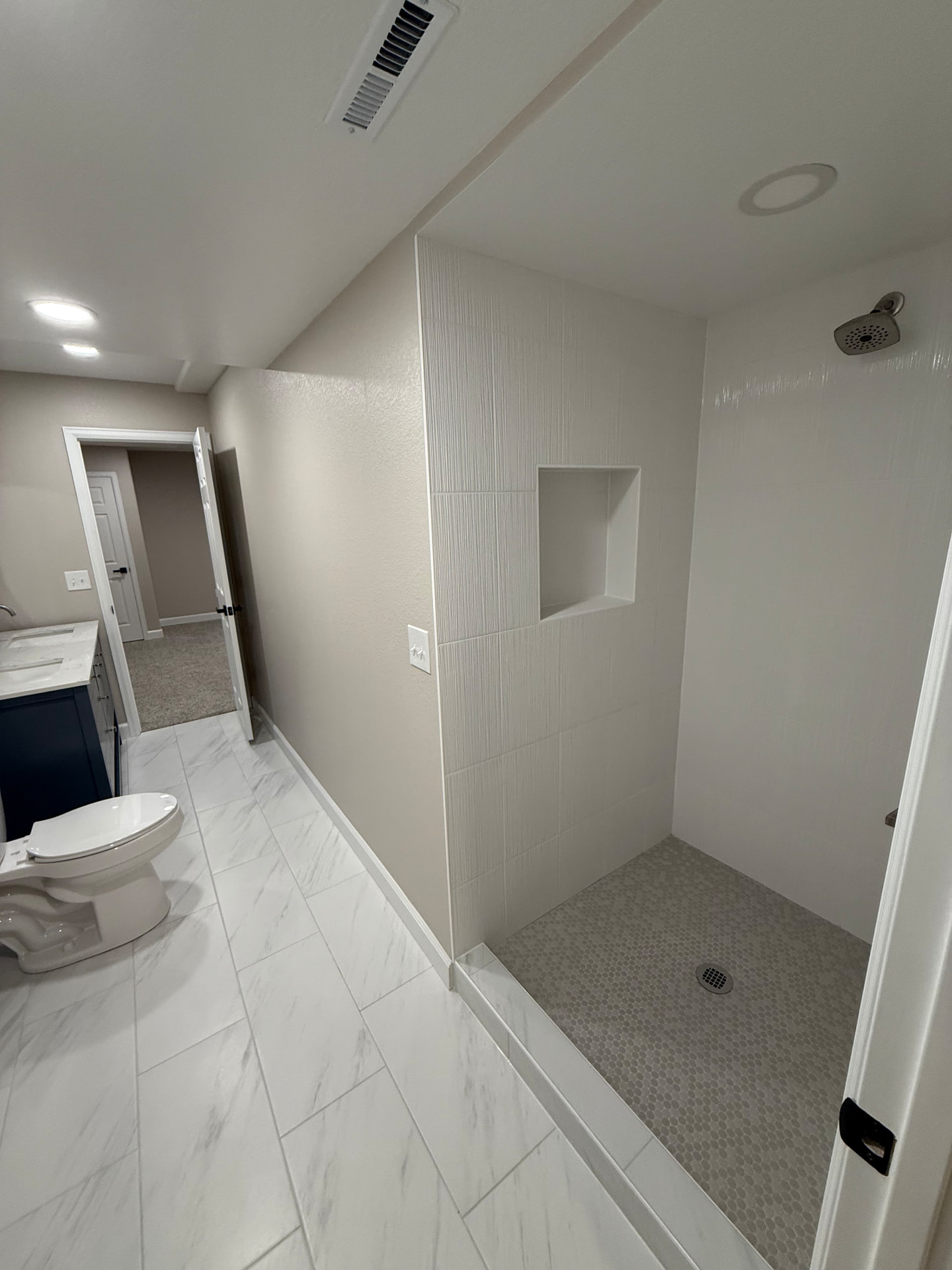 Finished basement bathroom with tiled walk-in shower and marble-look tile