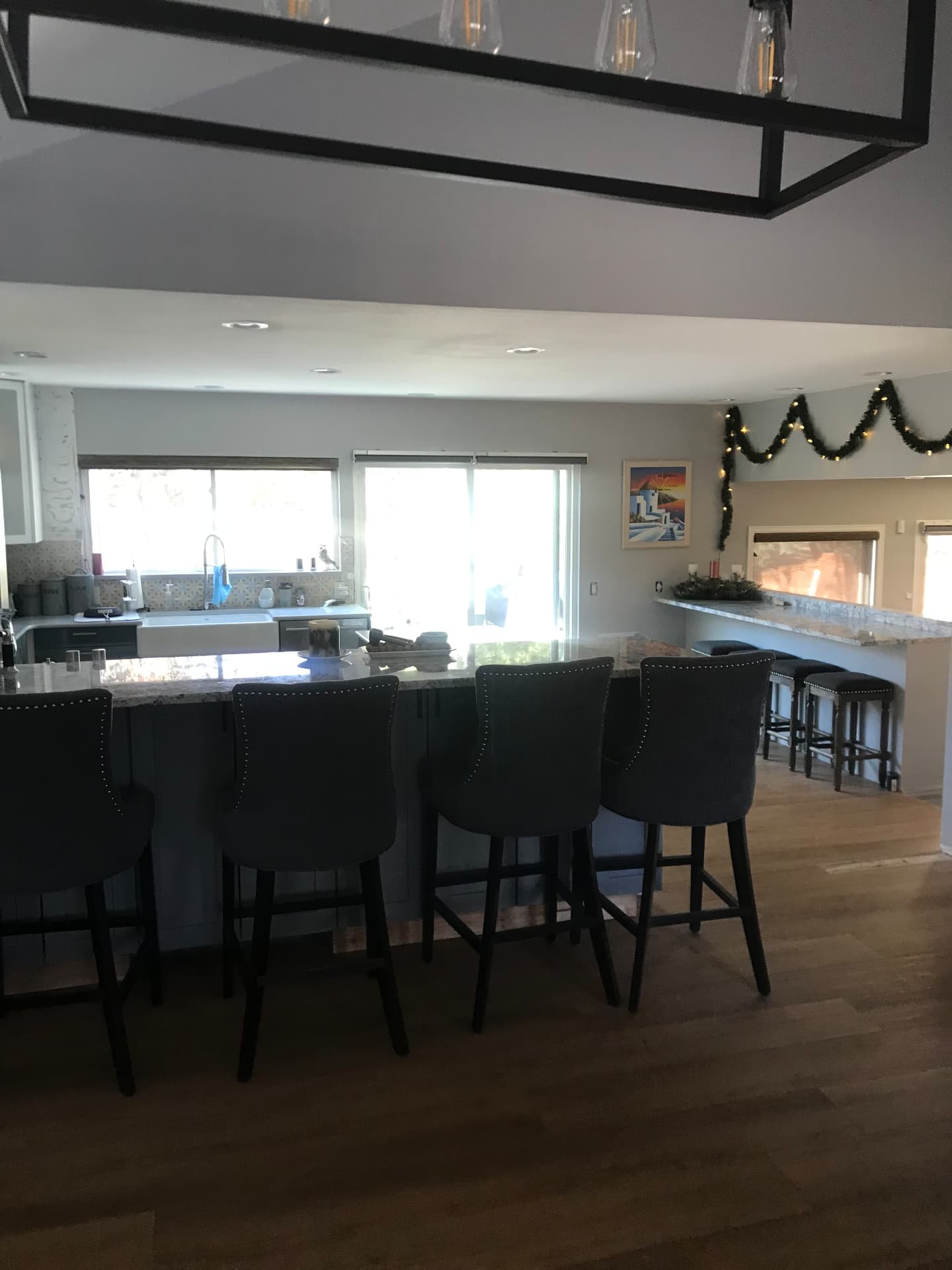 Open-concept kitchen with long granite island and upholstered bar stools