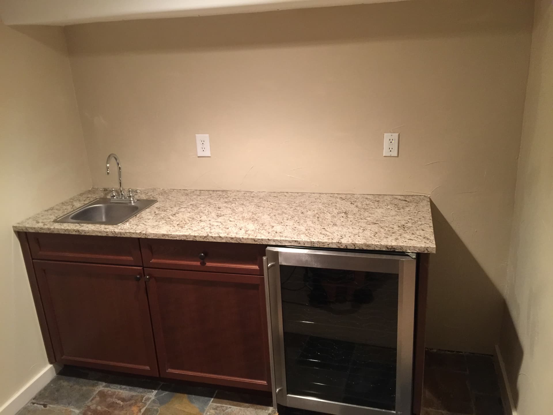 Basement wet bar with plain wall and granite counter before remodel