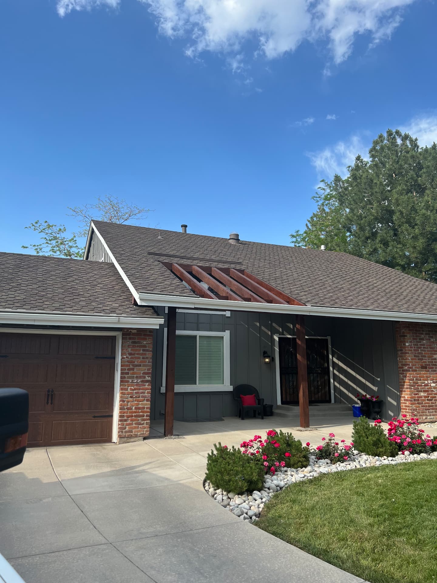 Home exterior with dark gray paint, cedar beams, and wood-tone garage door