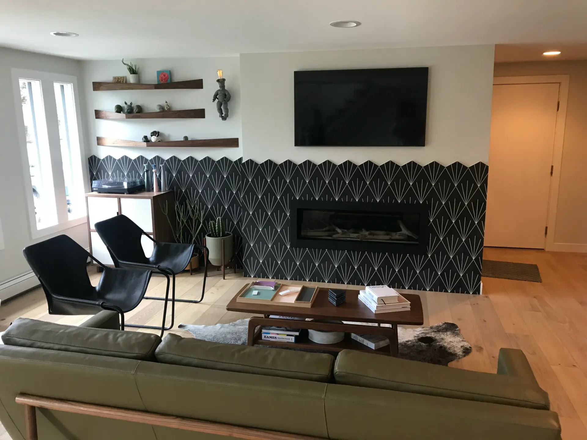 Finished living room with patterned fireplace wall, floating shelves, and seating by JR Burcham